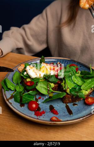 Das Buchweizenbrot wird mit einem pochierten Ei, einer in Scheiben geschnittenen Avocado, Garnelen, Tomaten und Salat geröstelt. Diätmenü. Flach liegend Stockfoto