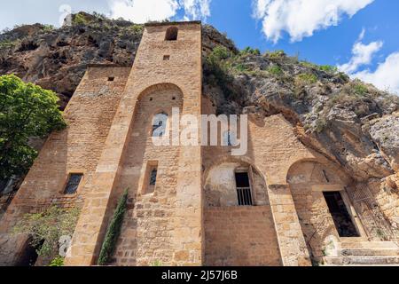 Historische antike Troglodytenkirche Saint-Cristofol und Glockenturm, verbunden mit festem Fels im mittelalterlichen Dorf Peyre. In Frankreich Stockfoto