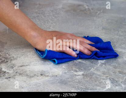 Frau, die den Tisch nach dem Abendessen mit einem Mikrofasertuch putzt Stockfoto