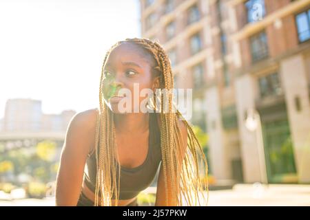 lateinisches hispanische Mädchen mit langen gelben Dreadlocks-Zöpfen, die draußen in stersten Straßen in der Stadt arbeiten Stockfoto