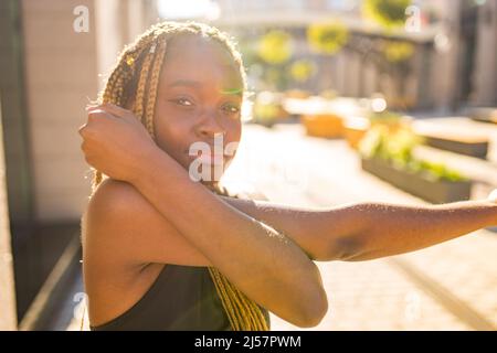 lateinisches hispanische Mädchen mit langen gelben Dreadlocks-Zöpfen, die draußen in stersten Straßen in der Stadt arbeiten Stockfoto