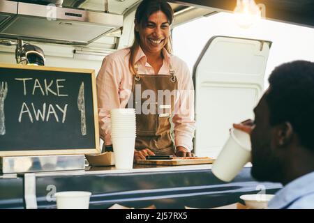 Hispanische reife Frau, die Essen zum Mitnehmen in einem Food Truck serviert – Hauptaugenmerk auf die Hände des Küchenchefs Stockfoto