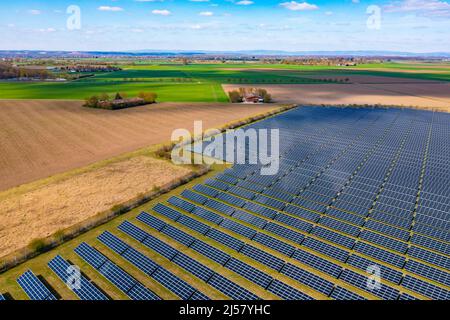 Drohnenansicht eines Solarparks mit Photovoltaikanlagen neben Feldern und einer Farm Stockfoto