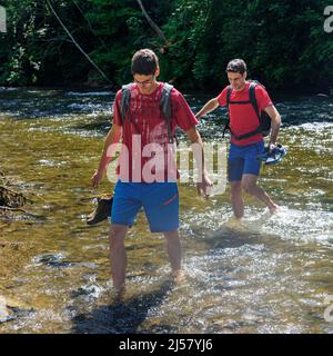 Eine Gruppe von Menschen Waten in einem Flussbett an einem heißen Sommertag im Allgäu Stockfoto