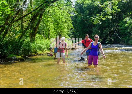 Eine Gruppe von Menschen Waten in einem Flussbett an einem heißen Sommertag im Allgäu Stockfoto