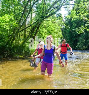 Eine Gruppe von Menschen Waten in einem Flussbett an einem heißen Sommertag im Allgäu Stockfoto