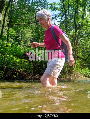 Eine Gruppe von Menschen Waten in einem Flussbett an einem heißen Sommertag im Allgäu Stockfoto