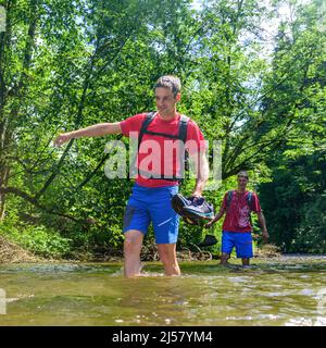 Eine Gruppe von Menschen Waten in einem Flussbett an einem heißen Sommertag im Allgäu Stockfoto