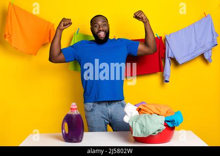 Portrait von schönen trendy fröhlich glücklich Kerl Hand waschen Kleidungsstück isoliert über hellen gelben Hintergrund Stockfoto