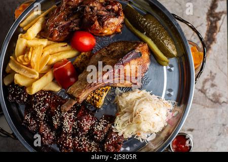 Köstliche Fleischplatte, Schweinerippchen, gegrilltes Hähnchen, Wurst, Rindfleisch, Gegrillte Kartoffeln. Mit Sauce verschiedene leckere gegrillte Fleisch mit Gemüse und Kräuter Stockfoto