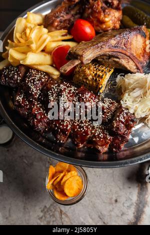 Köstliche Fleischplatte, Schweinerippchen, gegrilltes Hähnchen, Wurst, Rindfleisch, Gegrillte Kartoffeln. Mit Sauce verschiedene leckere gegrillte Fleisch mit Gemüse und Kräuter Stockfoto