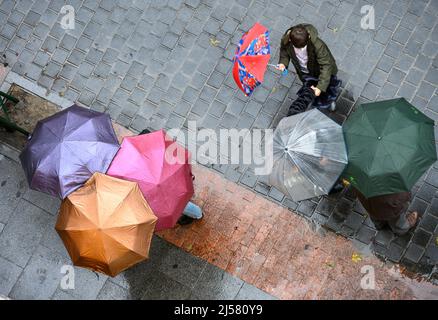 Gruppen von Menschen, die sich an einem regnerischen Tag in Madrid, Spanien, unter Regenschirmen unterhalten. Stockfoto