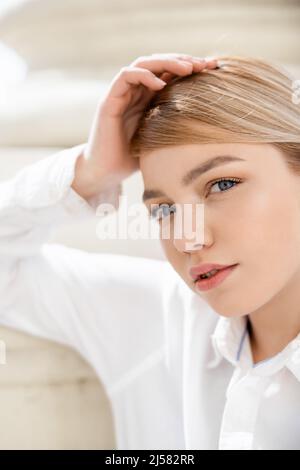 Porträt einer jungen blonden Frau, die im Freien auf die Kamera schaut Stockfoto