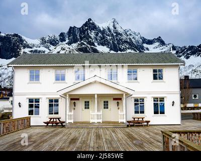 Norwegisches Holzhaus, schroffe Gipfel dahinter, Mefjordvaer, Senja Island, Troms, Norwegen Stockfoto