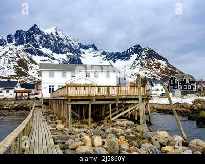 Holzhäuser an der Küste, schroffe Gipfel dahinter, Mefjordvaer, Senja Island, Troms, Norwegen Stockfoto