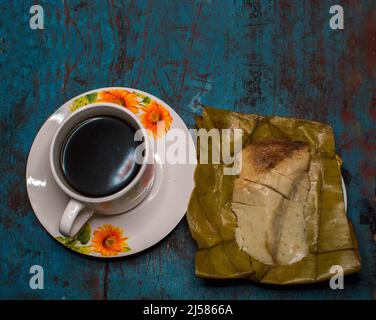 Gefülltes Tamale auf Holztisch serviert, gefülltes Tamale auf Bananenblatt serviert mit einer Tasse Kaffee auf Holztisch, typisch nicaragua Essen Stockfoto