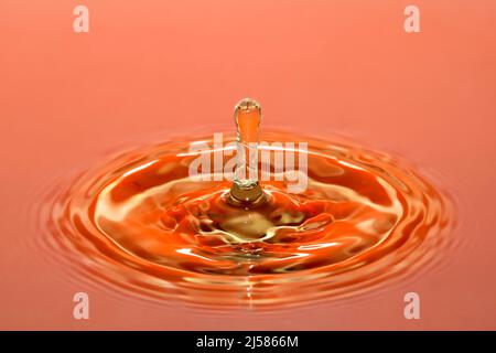 Tropfenfotografie, Wassertropfen fallen auf Wasseroberflaeche, Wassersaeule, Farbspiel, Studioaufnahme Stockfoto