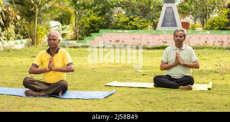 Breites Shoto von Senior man in namaste Pose auf Yoga-Matte - Konzept der älteren 60s Menschen Fitness, gesunde Lebensweise und morgendliche Routine. Stockfoto