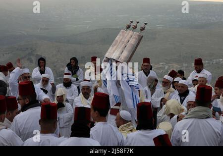 Nablus, die Stadt Nablus im Westjordanland. 21. April 2022. Ein Priester der alten samaritanischen Gemeinde hält während der Pilgerfahrt zum Passahtag auf dem Gipfel des Berges Gerizim in der Nähe der Stadt Nablus im Westjordanland am 21. April 2022 die Tora-Schriftrolle hoch. Quelle: Ayman Nobani/Xinhua/Alamy Live News Stockfoto