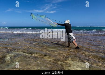 Ein Fischer wirft sein Netz in die Brandung am Haena Beach auf der Insel Kauai, Hawaii, USA. Stockfoto