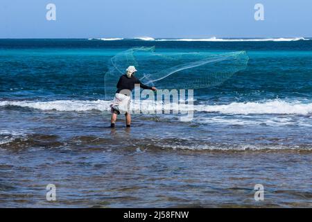 Ein Fischer wirft sein Netz in die Brandung am Haena Beach auf der Insel Kauai, Hawaii, USA. Stockfoto