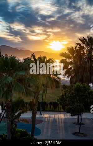 Sonnenaufgang über Meerwasser und Palmen in Torrox Costa, Costa del Sol, kleiner touristischer Ort zwischen Malaga und Nerja, Andalusien, Spanien Stockfoto