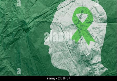 Männliche Kopf Silhouette und grünes Band Papier. Konzept des Monats des Bewusstseins für psychische Gesundheit. Als Symbol der Diognose und Prävention von psychischen Störungen. Stockfoto
