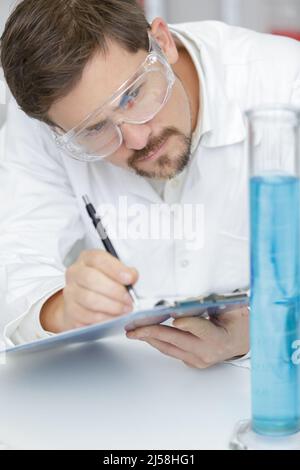 Konzentrierter Mann Wissenschaftler Notizen im Labor Stockfoto