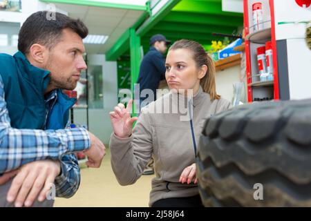 Junge Auszubildende wechselt Autoreifen in einer Garage Stockfoto