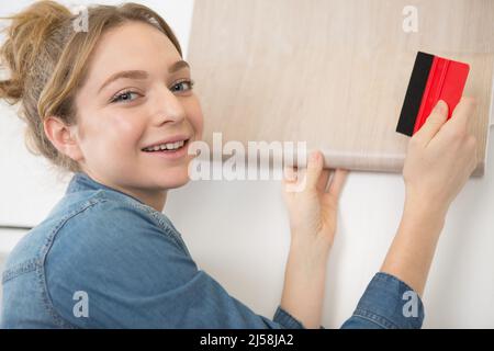 Frau klebend Furnier auf Schrank Stockfoto