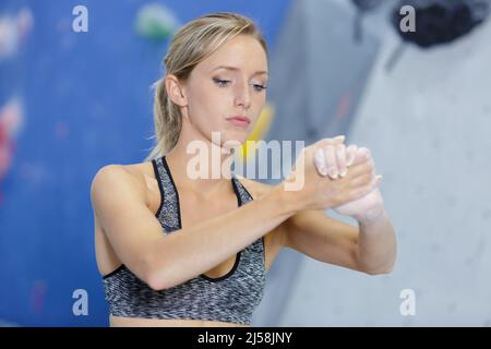 Sportliche Frau, die sich mit Magnesiumpulver an den Händen reibt Stockfoto