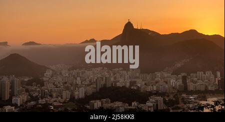 Herrlicher Sonnenuntergang über der Stadt, vom Zuckerhut aus gesehen, mit der Statue des Christuserlösers am Horizont. Rio de Janeiro, RJ, Brasilien. Stockfoto