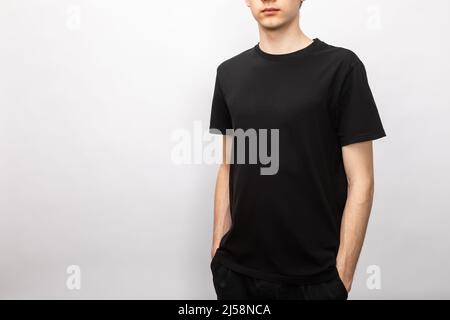 Junger, dünner Teenager, der ein leeres schwarzes Kurzarm-T-Shirt aus Baumwolle trägt Stockfoto