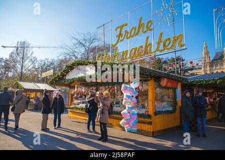 Outdoor-Szene von Menschen, die an einem sonnigen Tag auf dem berühmtesten Weihnachtsmarkt in Wien, Österreich, spazieren gehen Stockfoto