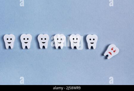 Zahnverlust. Die Zähne werden mit abgefallener Babymilch oder einem Erwachsenen auf blauem Hintergrund gereiht. Hohlraum, schlechte Mundhygiene, Zahnfleischentzündung, Trauma. Hochwertige Fotos Stockfoto