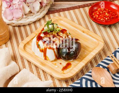 Konservierter Eiertofu in einer Holzplatte isoliert auf matter Seitenansicht auf Holztisch taiwan Lebensmittel Stockfoto