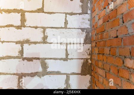 Eine weiße, belüftene Betonblockwand fügt sich in eine rote Ziegelwand ein Stockfoto