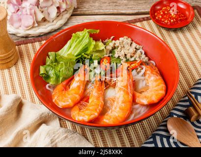 Frischer Shrimp Pho in einer Schüssel isoliert auf Matte Seitenansicht auf Holztisch taiwan Essen Stockfoto