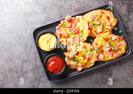 Knusprige Gemüsefritter mit Schinken aus der Nähe auf einem Teller auf dem Tisch. Horizontale Draufsicht von oben Stockfoto