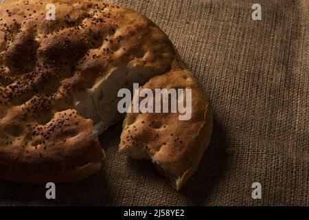 Nahaufnahme eines handgespaltenen Ramadan-Pitabrotes auf Jute-Hintergrund. Stockfoto