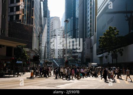 Hongkong, China. 21. April 2022. Menschen mit Gesichtsmasken überqueren die Straße. Hongkong lockerte einige seiner härtesten Maßnahmen zur sozialen Distanzierung am Donnerstag strömten viele Menschen in Einkaufszentren, Parks, Fitnessstudios und Restaurants, die nun zum ersten Mal seit mehr als drei Monaten zum Abendessen geöffnet haben. (Bild: © Keith Tsuji/ZUMA Press Wire) Stockfoto