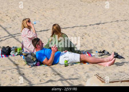 Weymouth, Dorset, Großbritannien. 21.. April 2022. Wetter in Großbritannien. Sonnenanbeter am Strand genießen die heiße Nachmittagssonne im Badeort Weymouth in Dorset. Bildnachweis: Graham Hunt/Alamy Live News Stockfoto