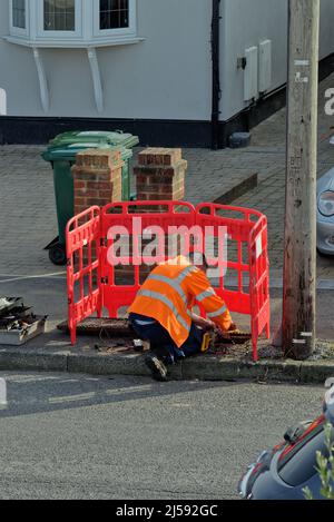 Ein Kommunikationsingenieur von BT Openreach, der an einer Telefonleitung in einer Vorstadtstraße in Surrey England arbeitet Stockfoto