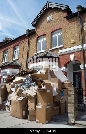 Vor einem viktorianischen Haus auf der mittleren Terrasse in twickemham, middlesex, england, stapelten sich Kartons mit ausrangierten Verpackungen und anderem Müll Stockfoto