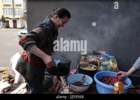 IRPIN, UKRAINE - 20. APRIL 2022 - Iryna Tschubatenko, eine Einheimische, die die russische Besatzung überlebt hat, kocht in einer provisorischen Küche, die sie mir organisiert hat Stockfoto