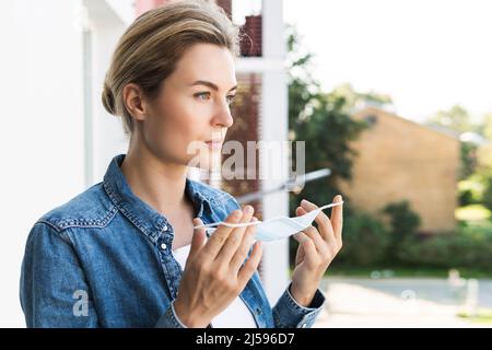 Die junge Frau geht nach draußen, um tief durchzuatmen, weil sie den ganzen Tag lang eine Präventionsmaske verwendet Stockfoto