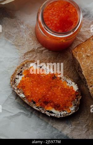 Sandwich mit rotem Kaviar auf Holzstruktur. Brot mit rotem Kaviar Stockfoto