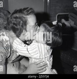 1961, historisch, ein kleines Mädchen in ihrem Pyjama, das ihrer Mutter vor dem Schlafengehen einen großen Kuss gab, Stockport, England, Großbritannien. Stockfoto