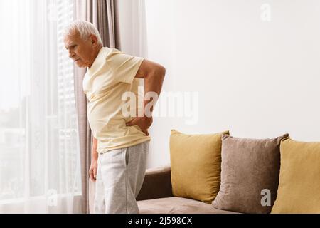 Der ältere Mann leidet unter Schmerzen im unteren Rücken zu Hause Stockfoto