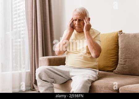 Älterer Mann leidet zu Hause unter Kopfschmerzen Stockfoto